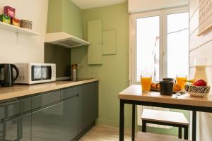 a kitchen with green walls and a table with a microwave at L'Odéon - Hypercentre - Gare SNCF in Nantes +10 photos