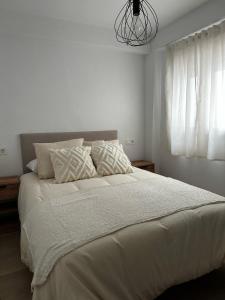 a bedroom with a large bed with white sheets and a chandelier at Apartamentos RoMar Campillos in Campillos