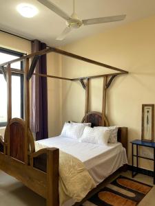 a bedroom with a canopy bed with white sheets and pillows at CITY Que2ens in Arusha