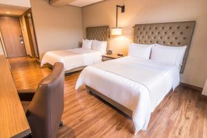 波哥大GHL Hotel Bogota Occidente的有两张床和一张书桌的酒店房间