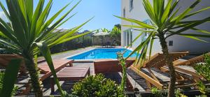 a swimming pool with wooden benches and palm trees at Aparthouse with pool in Solin