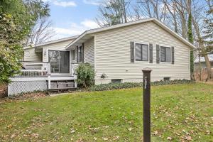 une maison blanche avec une cour avec un poteau dans l'herbe dans l'établissement Main Stay Cottage, à Saugatuck