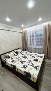 a bedroom with a bed with a black and white comforter at Двухкомнатная квартира в центре Сейфуллина 22 in Balqash