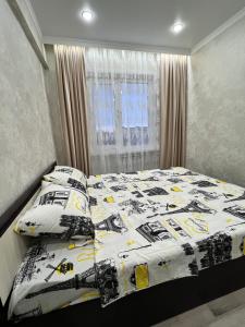 a bed with a black and white comforter and pillows at Двухкомнатная квартира в центре Сейфуллина 22 in Balqash +12 photos
