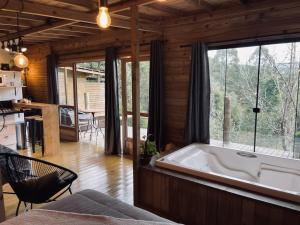 a large bath tub in a room with a large window at Vila dos Cedros in Rio dos Cedros