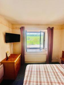 una camera con un letto, una finestra e una televisione di Hôtel Le Saint Martin a Bourg-Sainte-Marie Altre 5 foto