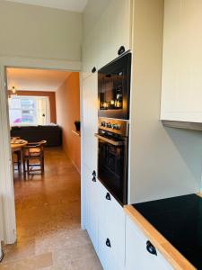 a kitchen with white cabinets and a black oven at Two bedroom apartment 150m from the beach in De Haan