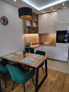 兹拉蒂博尔Ilic Prestige wellness & spa Zlatibor的厨房配有木桌和绿色椅子