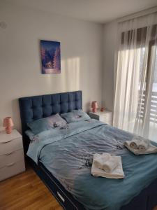 兹拉蒂博尔Ilic Prestige wellness & spa Zlatibor的卧室里有一张蓝色的床，床上放着毛巾