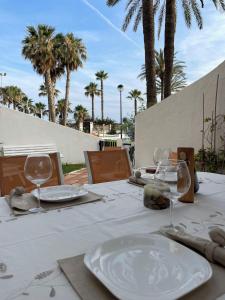 una mesa con platos y gafas blancos y palmeras en Lourdes House Beach, en Caleta de Vélez