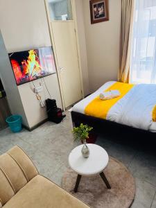 a room with a bed and a table and a couch at A modern affordable stylish bedsitter centrally located in nairobi in Nairobi