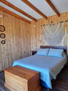 um quarto com uma cama e uma parede de madeira em Cabaña Refugio Magenta em Ñipas