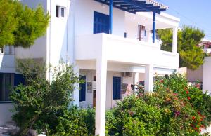 a white building with trees in front of it at Vaso Rooms in Livadakia +24 photos