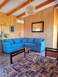 un divano blu in un soggiorno con pareti in legno di Cabaña Refugio Magenta a Ñipas