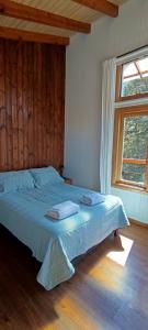 a bedroom with a bed with blue sheets and a window at Cabaña las Frutillas in San Martín de los Andes