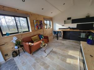 a living room with a couch and a kitchen at Cabanes en Loire, Gite & SPA en pleine nature in Veuzain-sur-Loire