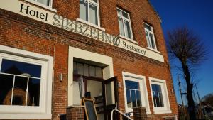 a red brick building with a hotel sign on it at Hotel Siebzehn80 in Carolinensiel