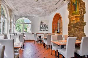 a dining room with tables and white chairs at Hotel Cavallino s'Rössl in Merano