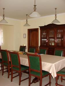 a dining room with a table and green chairs at Berezdtető Vendégház in Cserépfalu