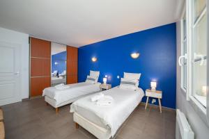 two beds in a room with a blue wall at Maison Chelona Peinte - nature & calme - Chelona'Loc in Saint-Ciers-du-Taillon