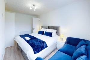 a bedroom with a bed and a blue couch at 3 Bed Bedford House Parking WiFi Sleeps 5 in Bedford
