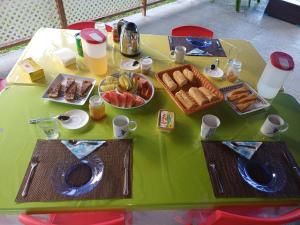 a green table with breakfast foods and drinks on it at Pitake Lodge 2 in Nuku Hiva