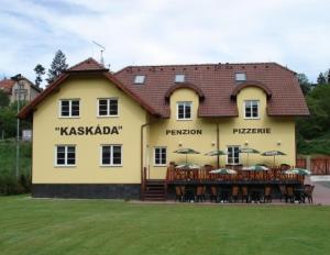 a large yellow building with tables and umbrellas at Guest House Kaskáda in Vrané nad Vltavou