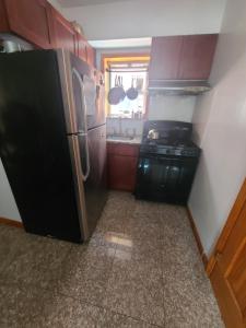 a kitchen with a black refrigerator and a sink at Nice rooms Woodside in Queens