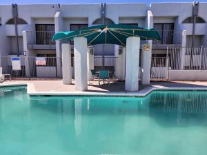 a pool with a umbrella and a table and chairs at Las palmas Hotel Tucson in Tucson