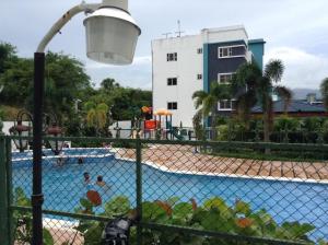 a fence with a swimming pool in front of a building at Cozy, comfortable three-bedroom condo in Santiago,DR in Santiago de los Caballeros