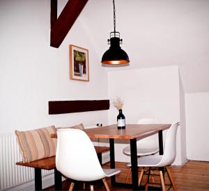 a dining room with a wooden table and white chairs at Lüner Apartment in Lüneburg
