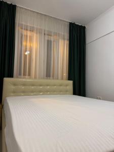 Schlafzimmer mit einem weißen Bett und grünen Vorhängen in der Unterkunft Central Modern Apartment in Oradea