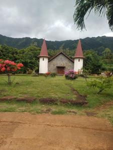 a house with two towers on a grass field at Pitake Lodge 2 in Nuku Hiva