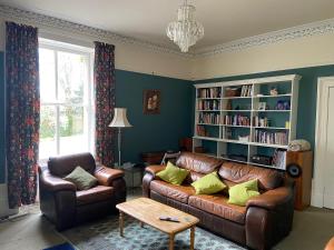un salon avec un canapé en cuir et une étagère à livres dans l'établissement Beautiful Listed Mansion with incredible woodland views, à Huntly