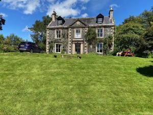 une vieille maison en pierre sur une cour herbeuse avec deux chiens dans l'établissement Beautiful Listed Mansion with incredible woodland views, à Huntly