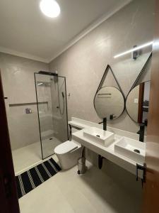 a bathroom with a shower and two sinks and a toilet at Hospedaria Casa Branca in Porto Seguro