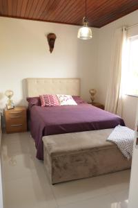 una camera da letto con un letto con lenzuola viola e una finestra di Casa 02 a Palhoça