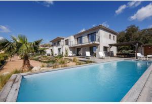 a large blue swimming pool in front of a house at Rondinara Camara - Lecci Lodge in Lecci