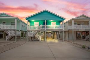 Una hilera de casas con balcones y una puesta de sol en Boogie Board Bungalow - Pet Friendly PRIVATE POOL, en Port Aransas