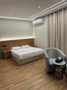 a bedroom with a bed and a chair at قمة راحتي للشقق المخدومة Qimat Rahaity SERVICED APARTMENTS in Yanbu