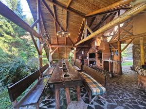 a wooden pavilion with a long table and benches at Cabana Daria Arieseni in Arieşeni