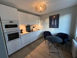 a kitchen with white cabinets and a table and chairs at Appartement avec Jacuzzi - Accès Piscine partagée in Criel-sur-Mer