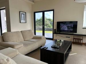 a living room with a couch and a tv at Deluxe House in Angra do Heroísmo