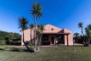 a house with palm trees in front of it at Villa Scilla - Pool & Garden in Plaia Grande