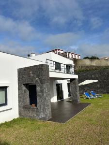 a white house with two blue chairs in a yard at Deluxe House in Angra do Heroísmo