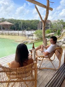 Un uomo e una donna seduti su un ponte di Kuunaa Tulum I Beer Sanctuary & Spa a Tulum