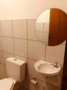 a bathroom with a toilet and a sink and a mirror at Apartamento Caminho da Praia in Parnaíba