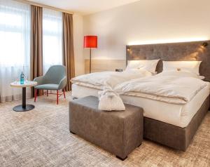 a large bedroom with a large bed and a chair at Trans World Hotel Columbus in Seligenstadt +40 photos