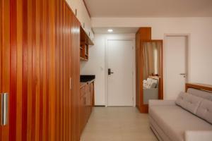 a living room with a couch and a kitchen at Estilo Itacaré - By Férias Itacaré in Itacaré
