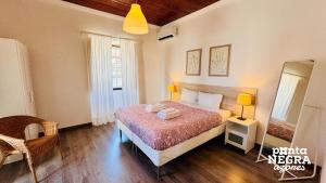 a bedroom with a bed and a chair and a mirror at Casa da Gente by PontaNegraAzores in Biscoitos